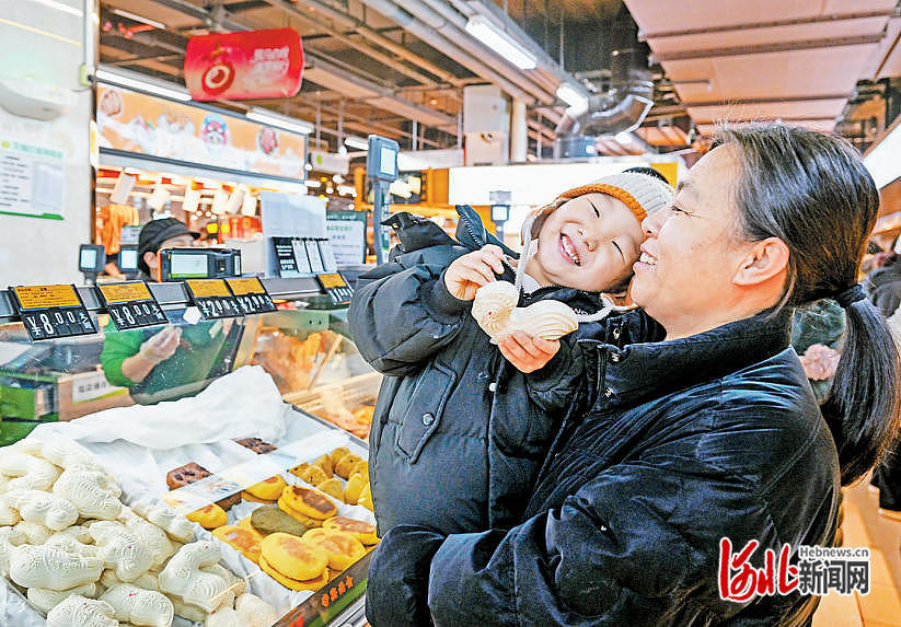 2月7日,小朋友在黄骅超市里品尝香甜的面花。