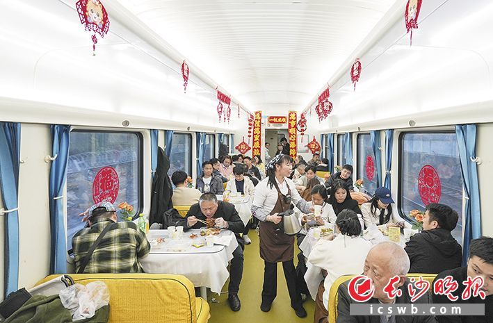 不少乘客来到餐车内就餐，热情的餐车阿姨给乘客添加着茶水。