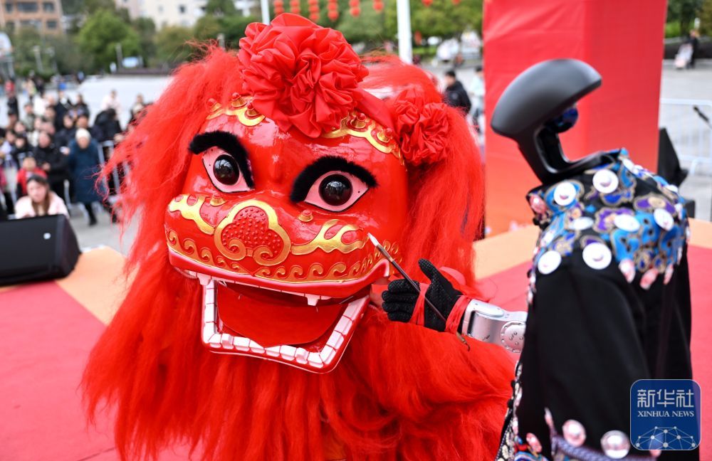 3月2日，在湖北省宣恩县人民广场，演员舞狮子与机器人进行互动。新华社发（宋文　摄）