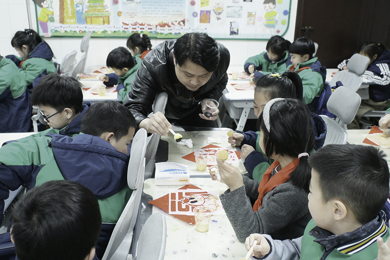 ▲在南昌市邮政路小学凤凰坡校区的手工实践活动中,老师指导学生进行非遗拓印。