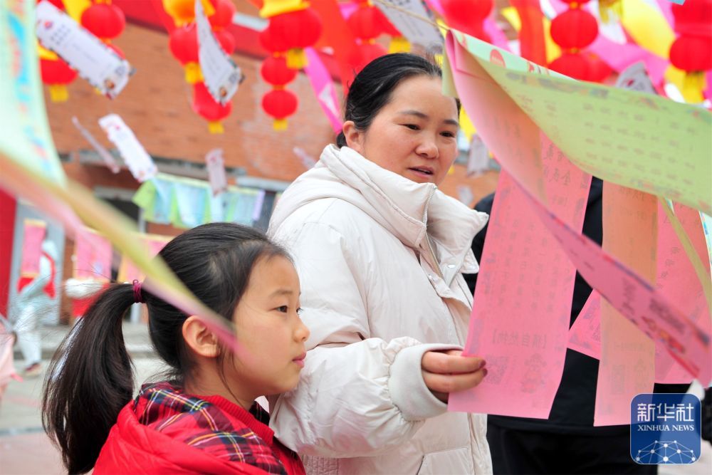 3月2日，一名家长带着孩子在湖北省宜昌市夷陵区灯会上猜灯谜。新华社发（张国荣　摄）