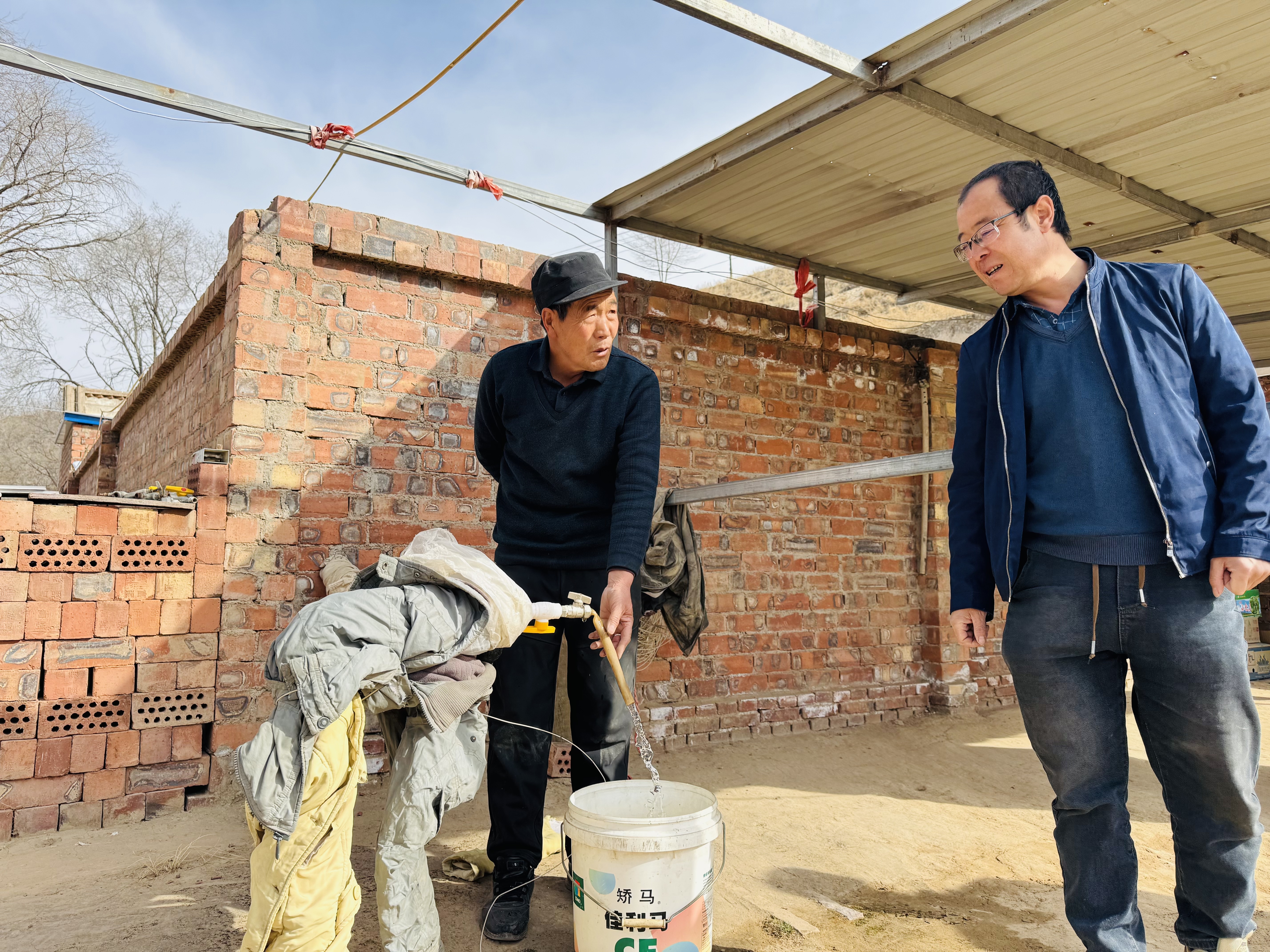 村民金积朝（左）正在接水