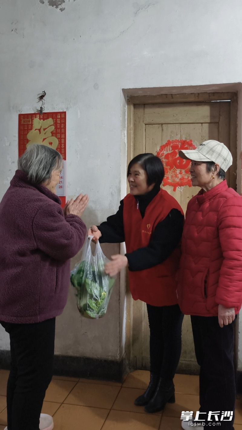 志愿者把自己种的小菜送给高龄老人。
