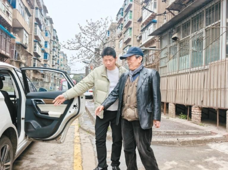 马重阳扶老人上车。