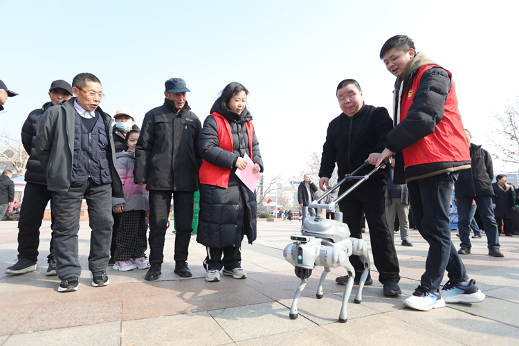 3月3日，在廊坊市区人民公园时代广场，群众在志愿者引导下体验智能导盲机器狗。董旭旭摄