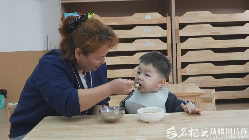 伊犁州托育综合服务中心保育员在给孩子喂饭（资料图片）。 伊宁市融媒体中心供图