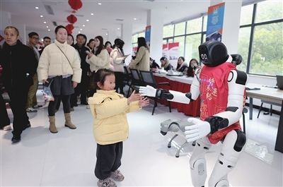 图2为萍乡技师学院工作人员现场操控机器人，引来众多求职者驻足关注。