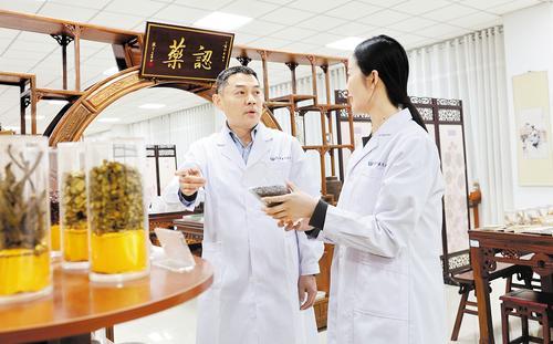 2月26日，在河北中医药大学中药文化传承基地，郭毅委员（左）与工作人员交流。 本报记者 张晶摄