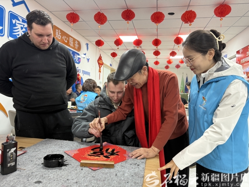 3月2日,志愿者吴泽虎教外国司机写书法。石榴云/新疆日报记者 白素君摄