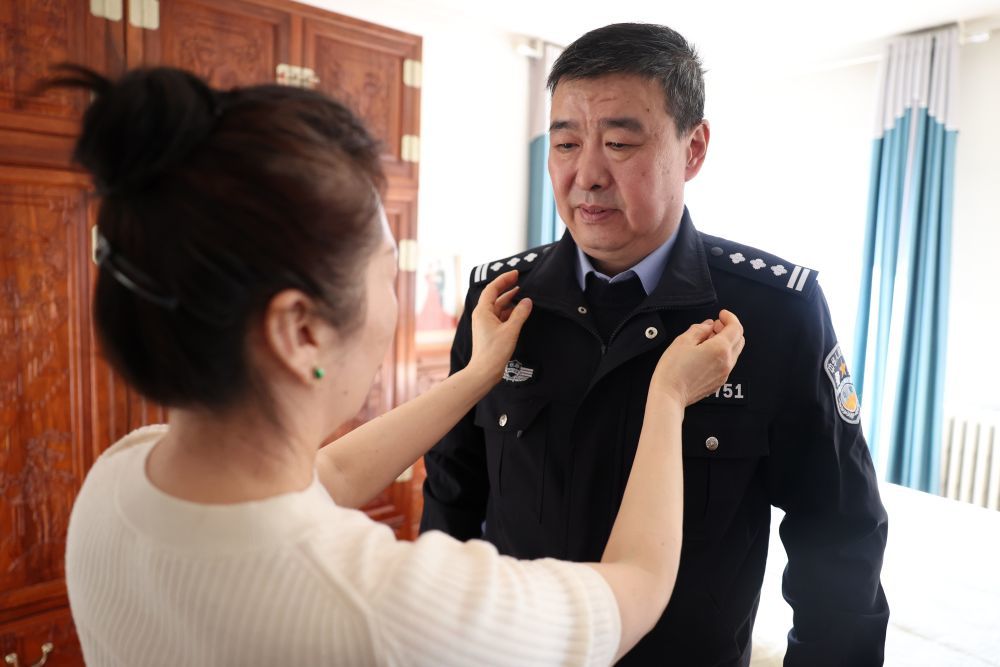 最后一次值乘前，妻子王春兰（左）为段文革整理警服（3月11日摄）。新华社记者　陈斌　摄