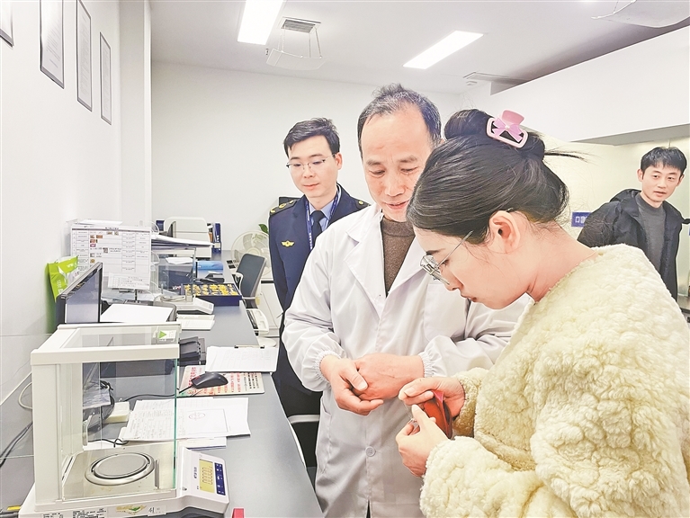 市民拿刚买的金饰给工作人员进行检测。 本报全媒体记者 蔡颖辉摄