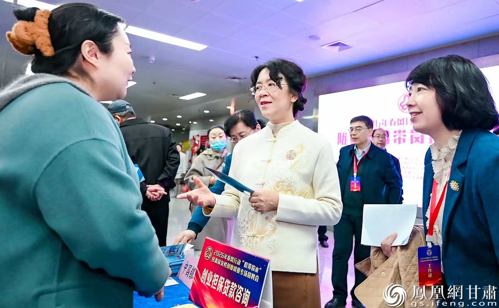 甘肃省妇联主席马琨（中）与招聘会驻场金融机构工作人员交谈，详细了解支持女性创业就业相关金融政策。