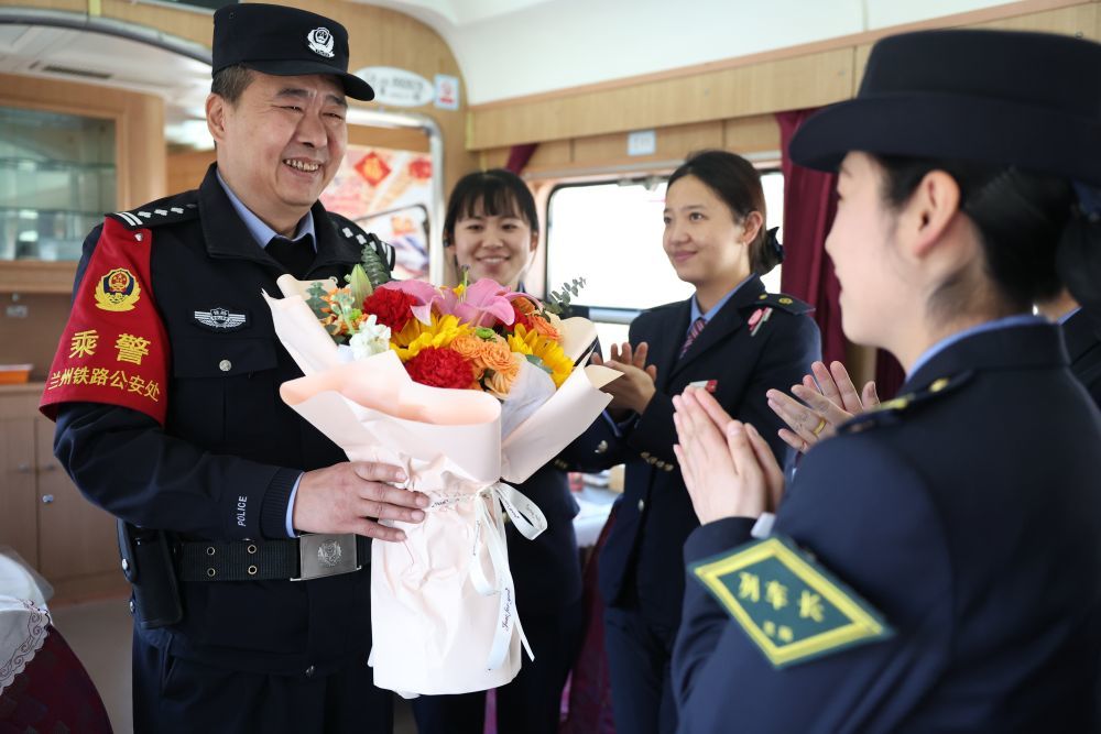 3月11日，列车工作人员在兰州开往上海的T118次列车上向最后一次值乘的兰州铁路公安处乘警支队民警段文革（左一）献花并送上祝福。新华社记者　陈斌　摄