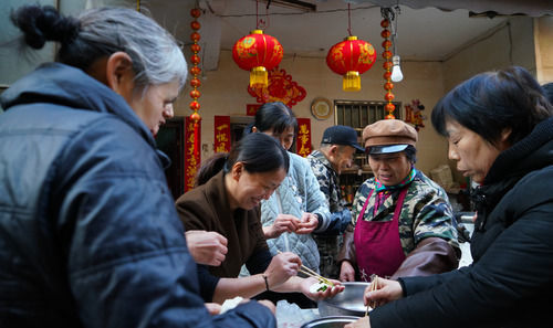 熊庚香（右二）和前来烧饭的百姓在厨房内包饺子。
