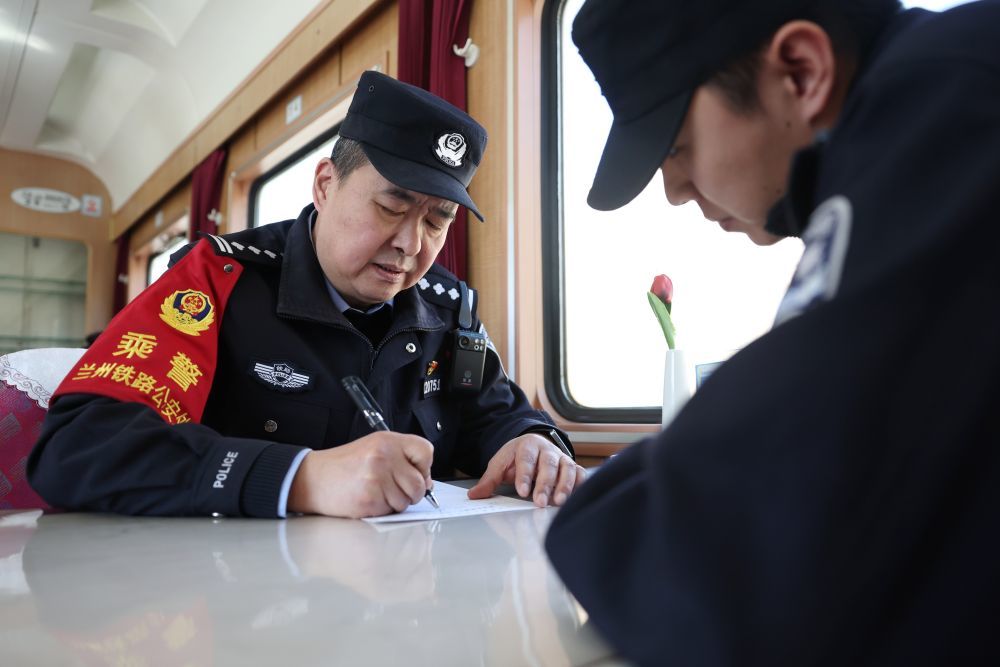 3月11日，兰州铁路公安处乘警支队民警段文革（左）在兰州开往上海的T118次列车上填写工作日志。新华社记者　陈斌　摄