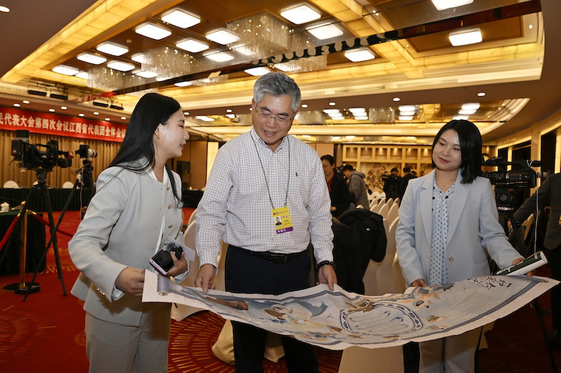 3月6日下午，十四届全国人大四次会议江西代表团举行全体会议，并向境内外记者开放团组。图为加拿大轻松传媒副总裁高俊峰关注江西日报手绘长卷《一炉窑火 何以千年》。大江新闻全媒体记者王祺 摄