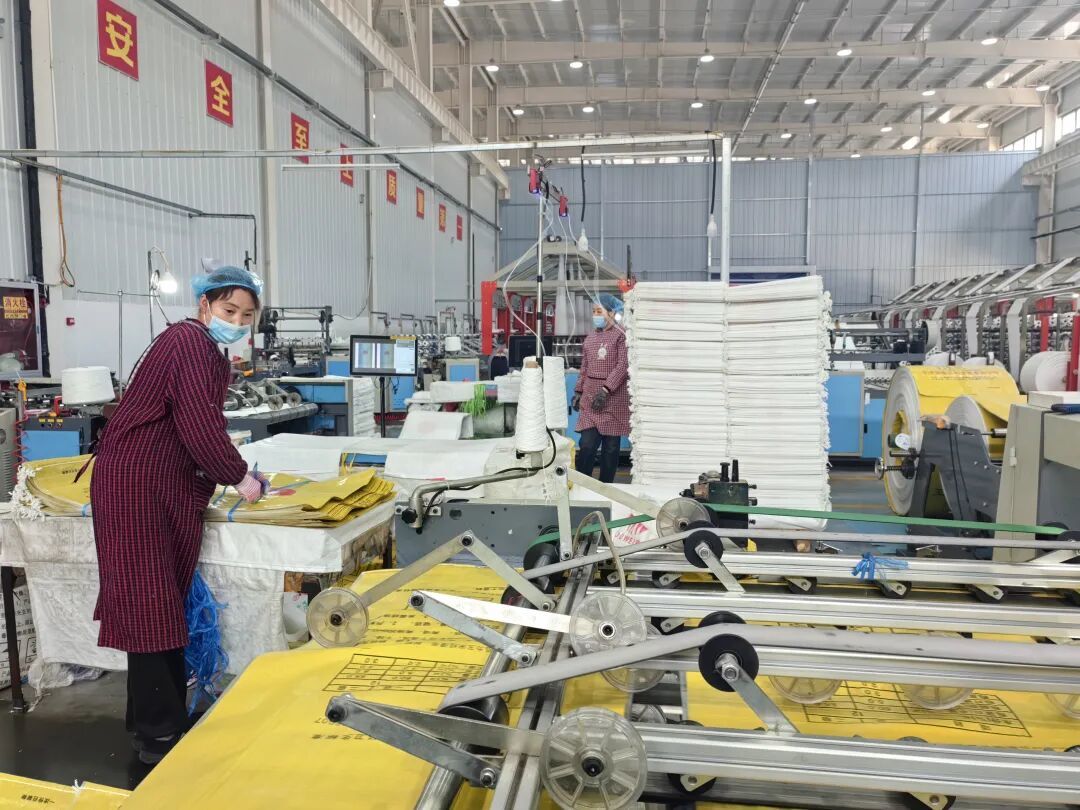 三力明塑业有限公司的工人们正在裁缝编织袋