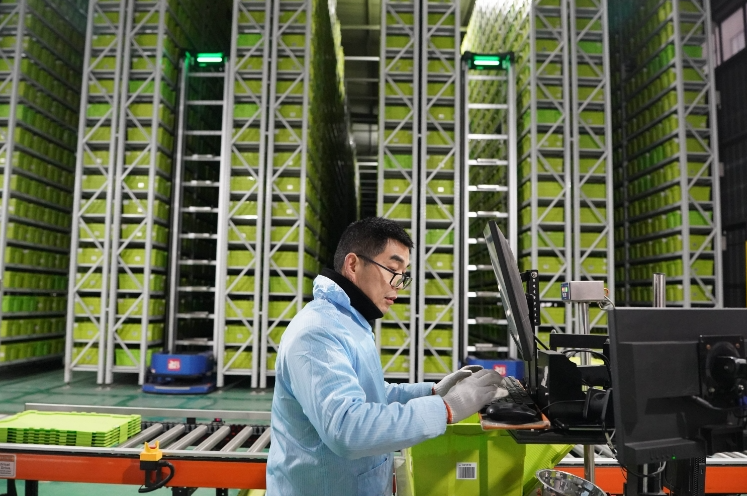 在江西瑞金漫格科技有限公司库房内,工作人员操作智能机器人抓取积木产品进行打包。图源新华社