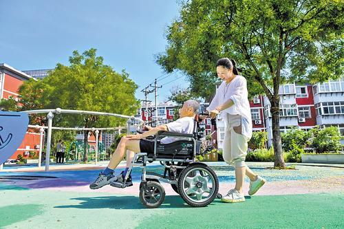 2025年7月4日，邯郸市复兴区阳光里棉三小区，社区工作人员陪伴行动不便的居民在进行了适老化改造的场地上活动。（资料片）本报记者 田明摄