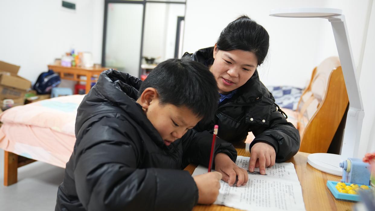 致知楼的一名房客正在辅导儿子做功课。新华社记者袁慧晶 摄