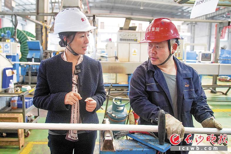生产车间内，毛冰花（左）与工作人员讨论电缆生产情况。长沙晚报全媒体记者 刘晓敏 摄