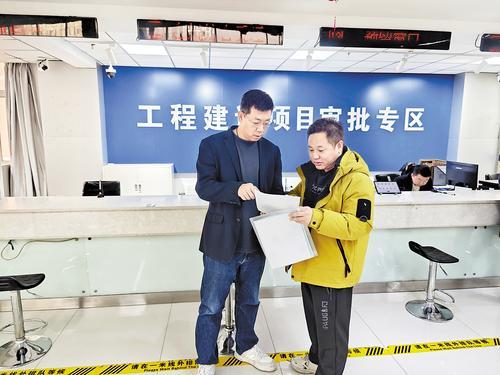 3月10日,在张家口经开区政务服务中心办事大厅,经开区数据和政务服务局规划国土股股长范小强(左)正在给前来办事的企业人员介绍虚拟审批流程。 本报记者 许卫兵摄