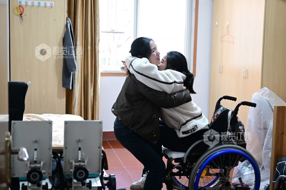 3月12日，在安徽师范大学宿舍，占群燕艰难却熟练地抱起许詹琪，把她放到康复设备上进行站立训练。