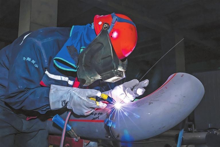 甘肃巨化新材料有限公司高性能硅氟新材料一体化项目建设现场，工人进行设备焊接作业。