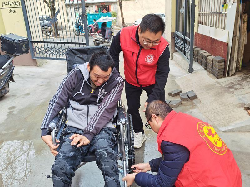 图为冯恺（中）与张清（右）为魏超调试轮椅。（受访者供图）