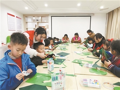 志愿者指导孩子们开展剪纸活动