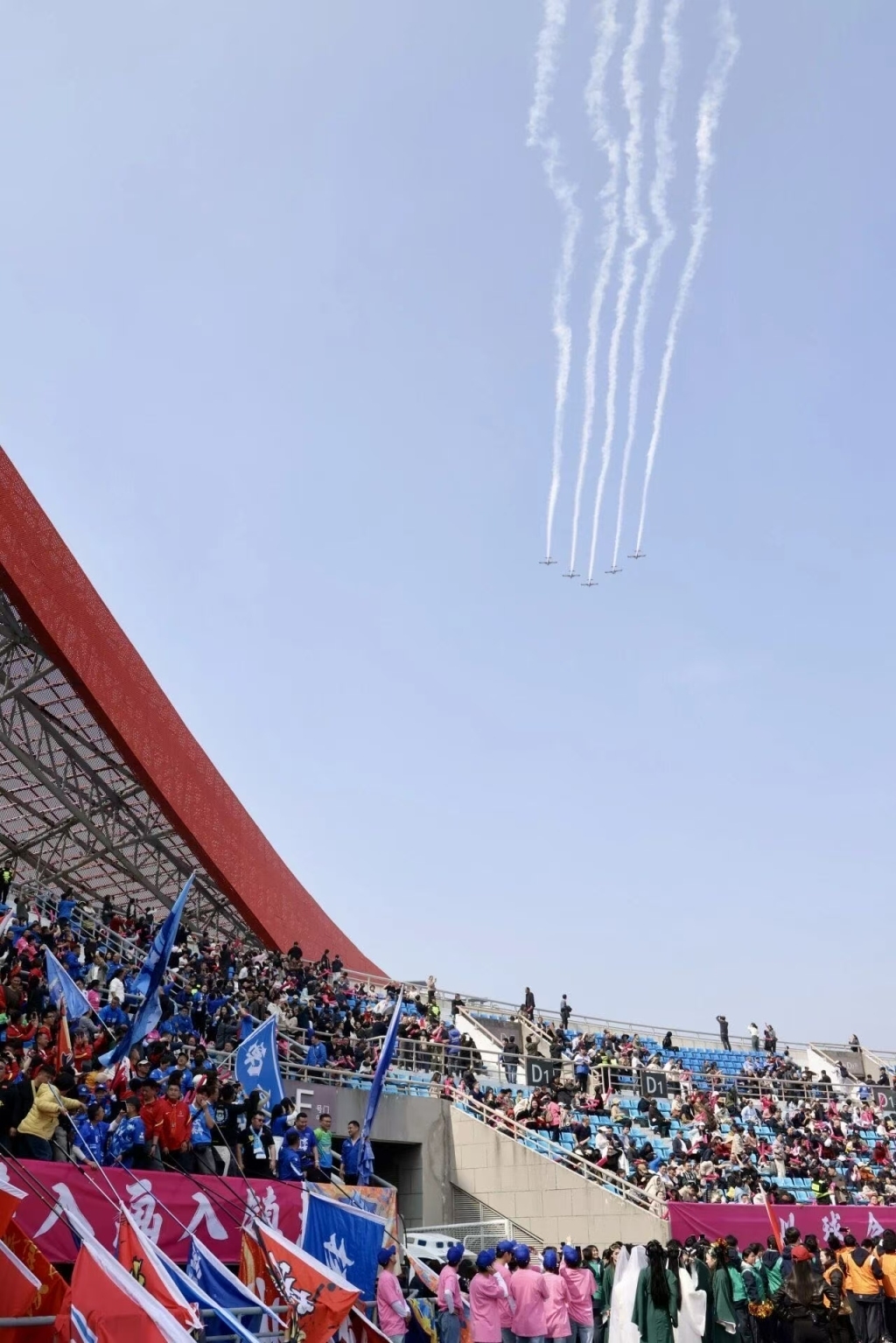 镇江“刷飞机”迎接远方来客。友谊赛前，飞行表演队在体育场上空编队通场。镇江发布供图