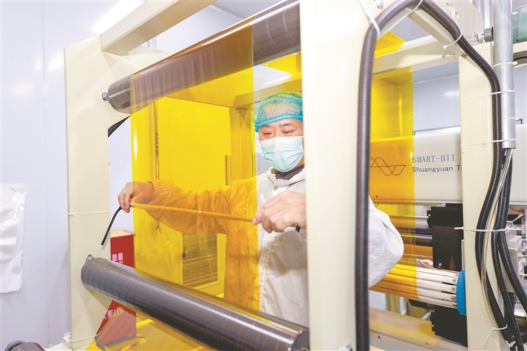 位于共青城高新区的江西民强新材料技术有限公司生产车间内，工人在观察聚酰亚胺薄膜生产情况。本报全媒体记者 吴福清摄