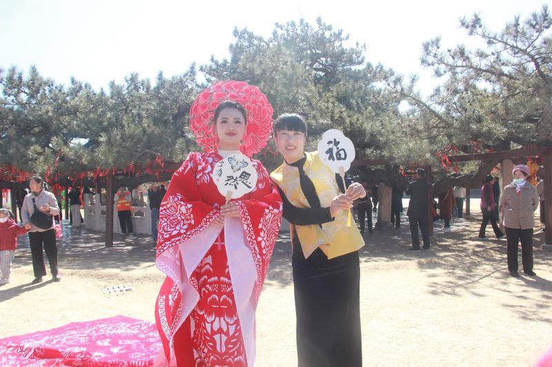 游客与身着丰宁满族剪纸汉服的女子拍照合影。