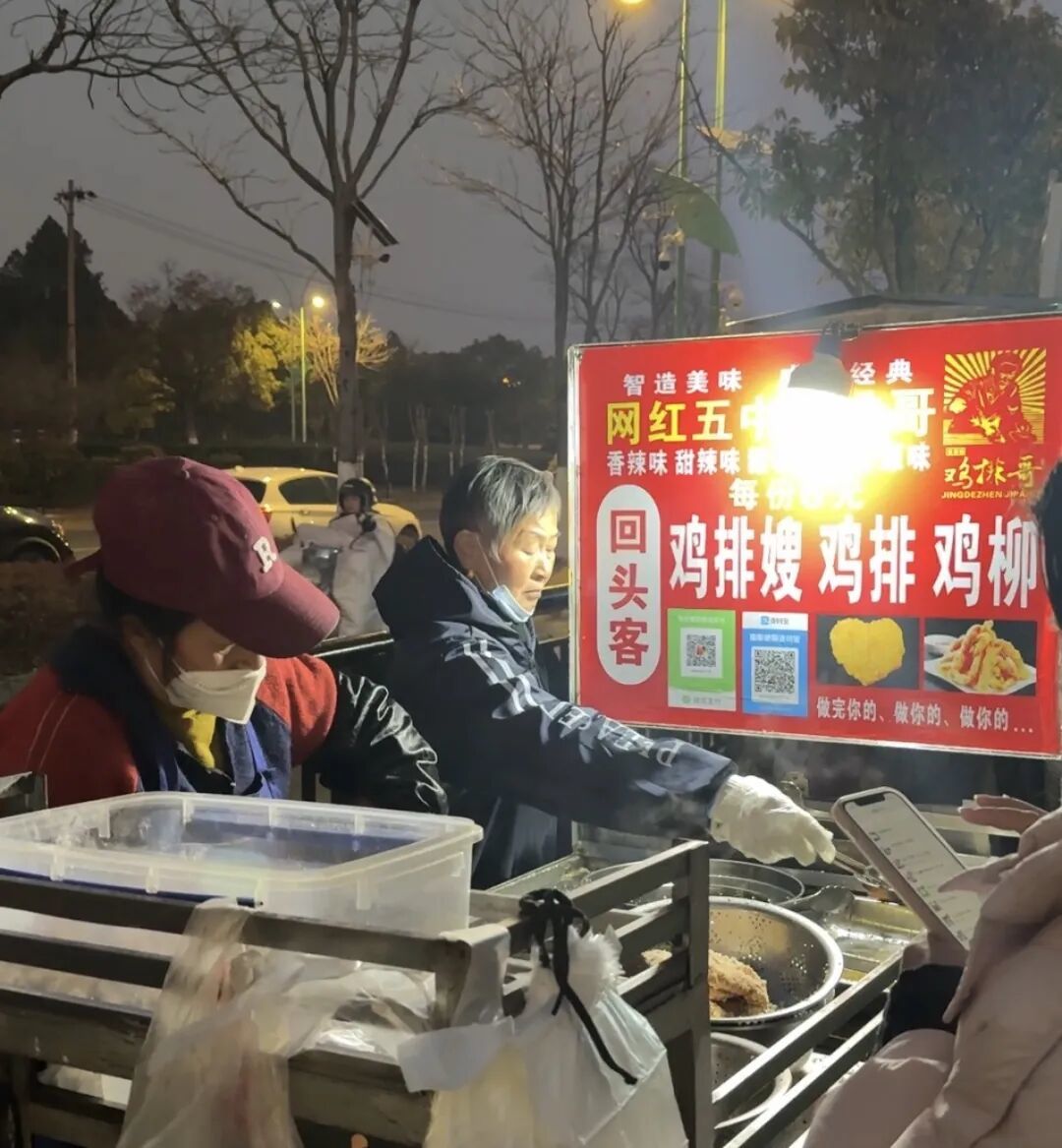 寒冬夜晚,“鸡排哥”的妻子和母亲仍在出摊。图片摄于2026年1月23日