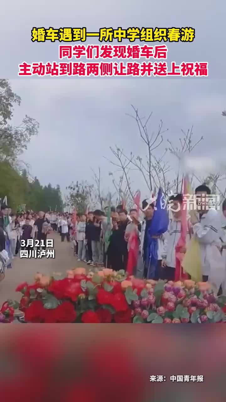婚车遇到一所中学组织春游 同学们发现婚车后 主动站到路两侧让路并送上祝福