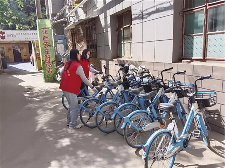 社区工作人员摆放小区里的共享单车