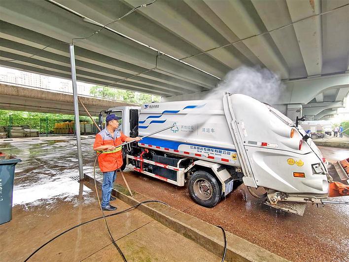 武汉三环线烽火路高架桥下,环卫工给垃圾清运车洗澡