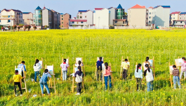 吉安市吉州区樟山中心小学学生们在油菜花田间写生。李军/摄