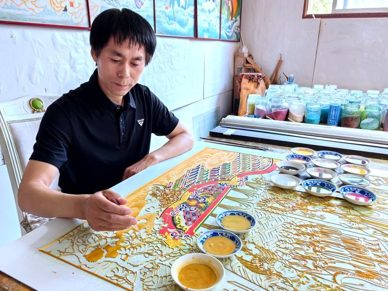 传承人正在绘制金银丝沙画。