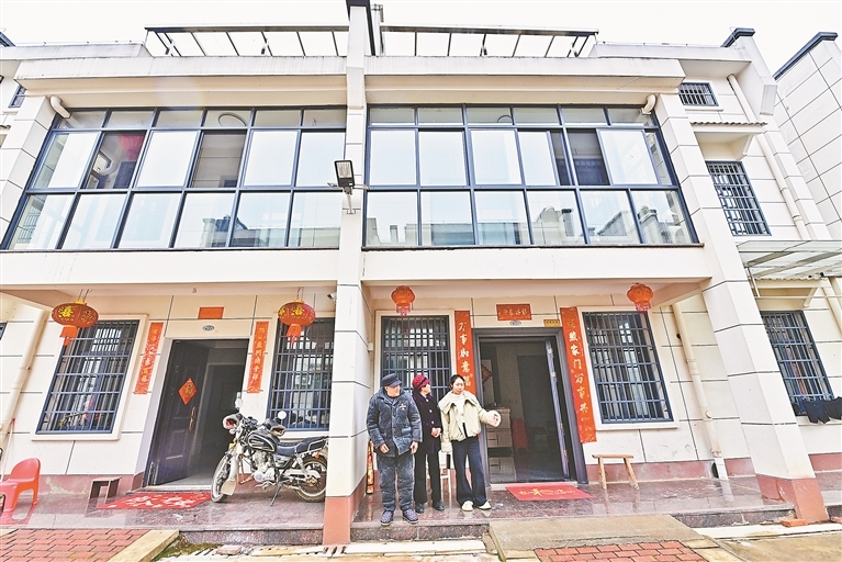 安置户张为民和家人在新家前聊天。