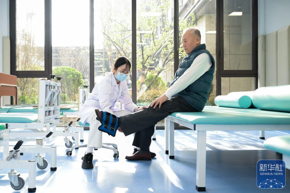 3月25日，在济南市历下区槿椿泺园，康复治疗师辅助老人进行下肢抗阻训练。新华社发（杜厚平 摄）