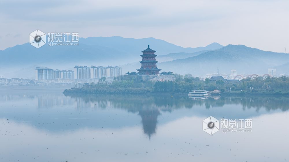 2026年3月30日,江西省吉安市吉水县清晨下完雨后,水面平静得像一面镜子,岸边的建筑倒映在水中与空中的云雾形成一幅江南画卷。