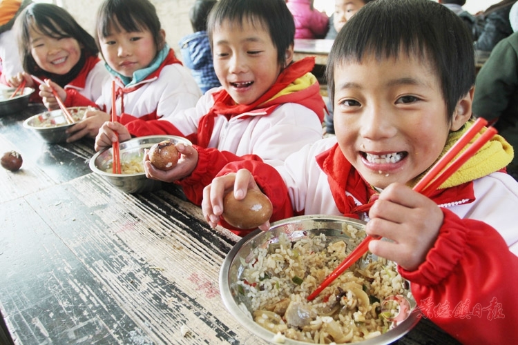 孩子们正开心地吃着热气腾腾的免费午餐。