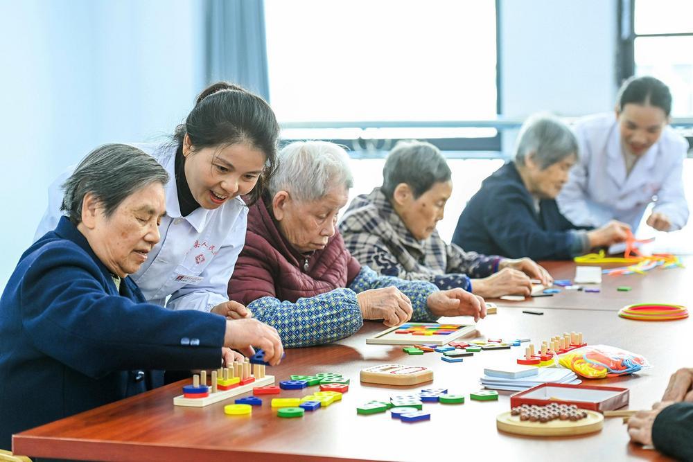 宜丰县总医院人民医院分院医养中心的医护人员在陪着老人做益智游戏。 (本报记者 周 亮 摄)