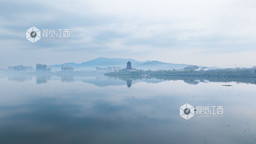 2026年3月30日,江西省吉安市吉水县清晨下完雨后,水面平静得像一面镜子,岸边的建筑倒映在水中与空中的云雾形成一幅江南画卷。