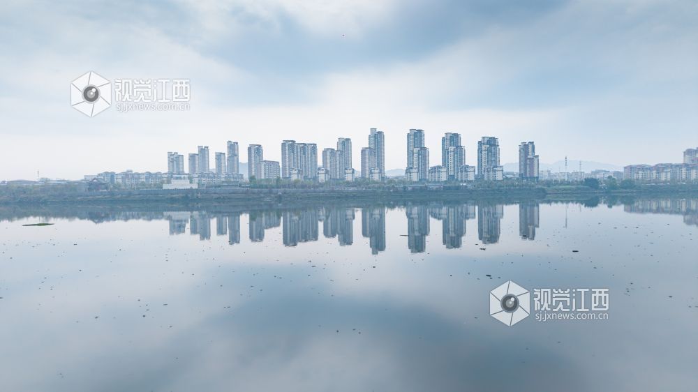 2026年3月30日,江西省吉安市吉水县清晨下完雨后,水面平静得像一面镜子,岸边的建筑倒映在水中与空中的云雾形成一幅江南画卷。