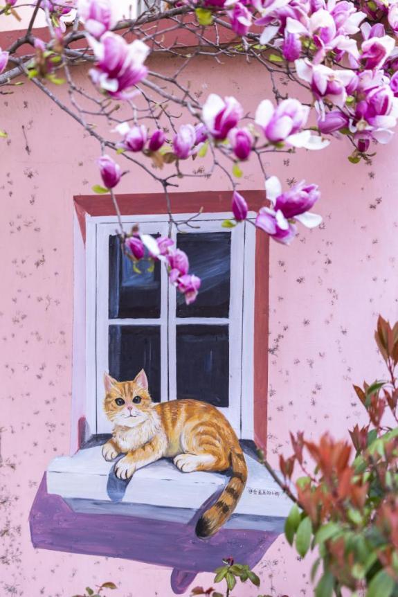 紫玉兰枝斜搭下来,与墙绘浑然一体。画里画外的春,都浸在这甜软的氛围里。单英 摄