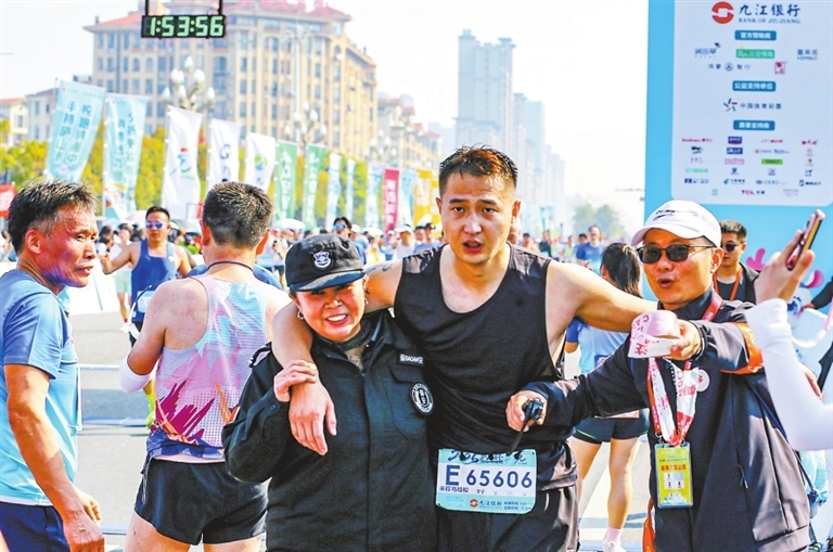 工作人员搀扶完赛跑者前往休息区域。(九江日报记者 欧阳海员 摄)