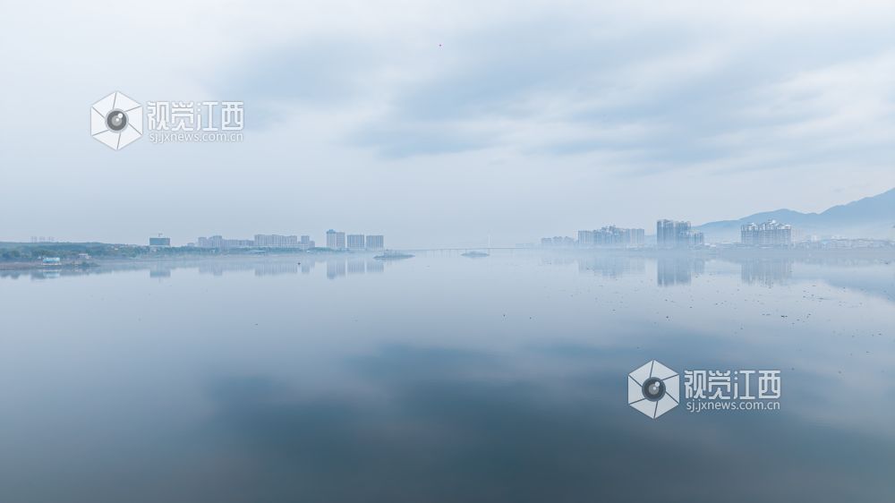 2026年3月30日,江西省吉安市吉水县清晨下完雨后,水面平静得像一面镜子,岸边的建筑倒映在水中与空中的云雾形成一幅江南画卷。