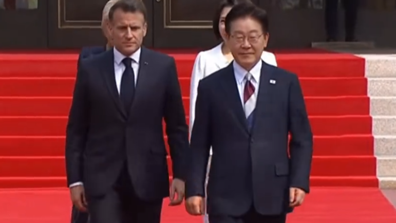 马克龙访问韩国，李在明戴红白蓝三色领带迎接，马克龙向挥舞国旗欢迎的小朋友送飞吻